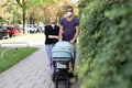 Worried young parent walking on empty street with stroller wearing medical masks to protect them from corona virus