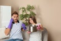 Worried young woman collecting water leakage from ceiling while her husband calling plumber Royalty Free Stock Photo