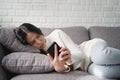 Worried young woman crying lying on couch holding and look phone waiting for call message. She is sad after an argument with her Royalty Free Stock Photo