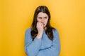 Worried young woman folded hands together near mouth, gnawing nails, female feels uncertain, stressed