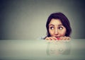 Worried young woman looking at something peeking from under the table