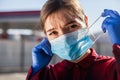 Worried young woman putting PPE face mask on/taking it off in public