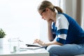 Worried young woman using calculator and counting her savings while sitting on sofa at home Royalty Free Stock Photo