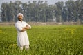 worry less indian farmer standing hand folded in his healthy wheat field