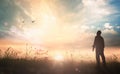 Humble man standing on sunlight with meadow autumn sunset