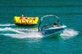 WORTHERSEE, AUSTRIA - AUGUST 08, 2018: Happy young people, on inflatable attractions, drive behind a motorboat on the lake.