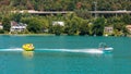 WORTHERSEE, AUSTRIA - AUGUST 08, 2018: Happy young people, on inflatable attractions, drive behind a motorboat on the lake