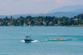 WORTHERSEE, AUSTRIA - AUGUST 08, 2018: Happy young people, on inflatable attractions, drive behind a motorboat on the lake