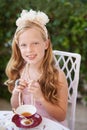 Would you like to join me for tea. A young girl playing dress up with a tea cup in front of her in her garden. Royalty Free Stock Photo