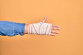 Wounded hand of caucasian young woman cover with bandage doing number five with fingers over isolated yellow background