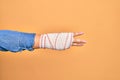 Wounded hand of caucasian young woman cover with bandage doing number three with fingers over isolated yellow background