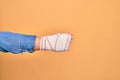 Wounded hand of caucasian young woman cover with bandage doing punch gesture showing fist over isolated yellow background Royalty Free Stock Photo