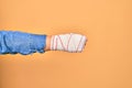 Wounded hand of caucasian young woman cover with bandage doing punch gesture showing fist over isolated yellow background Royalty Free Stock Photo