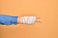 Wounded hand of caucasian young woman cover with bandage doing victory sign over isolated yellow background