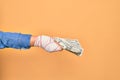 Wounded hand of caucasian young woman cover with bandage holding bunch of dollars banknotes over isolated yellow background