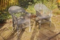 Woven armchairs outside in a rustic garden with green plants for relaxing after gardening. Yard landscape with two