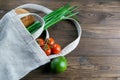 Woven bag of different health food on dark wooden table background. Bread, green onion, garlic, tomato and yellow peper. Top view Royalty Free Stock Photo