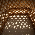 A woven basket creates an intricate pattern of light and shadow on a white surface. Royalty Free Stock Photo