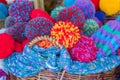 A woven basket full of bright knitted caps with large pompoms