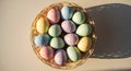 A woven basket overflowing with colorful, striped Easter eggs, casting a textured shadow on a warm, neutral surface, celebrating Royalty Free Stock Photo