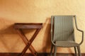 Woven chairs and a wooden table stand against a rugged concrete wall. Royalty Free Stock Photo