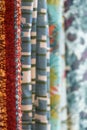 Woven fabrics with different colored patterns hanging for sale in a row, copy space, selected focus