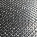 Woven metal wire mesh in a grid pattern covers a dark textured surface Royalty Free Stock Photo