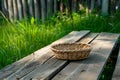 woven picnic basket on a wooden table bench, green grass around Royalty Free Stock Photo