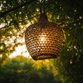A woven rattan lantern hangs from a bamboo support, illuminated from within, Royalty Free Stock Photo