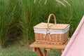 Woven wood picnic basket on small wooden table in park. Summer sunny day and picnic time concept Royalty Free Stock Photo