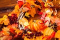 Woven wreath decorated orange leaves, autumn berries and vegetables: pumpkins, corns, mushrooms, peppers, garlic at the wooden bo