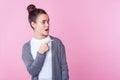 Wow, advertise here! Portrait of wondered teenage girl looking with open mouth in surprise, pointing to the side. pink background