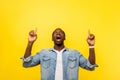 Wow, advertise there! Portrait of surprised happy man pointing up. studio shot isolated on yellow background