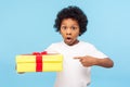 Wow, awesome holiday present! Portrait of amazed cute little boy with curls pointing to gift box