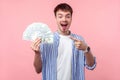 Wow big money! Portrait of excited amazed brunette man pointing at money. indoor, isolated on pink