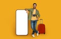 Cheerful man traveler posing by big smartphone, mockup