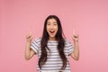 Wow, look above at advertisement! Portrait of pleasantly surprised girl in striped t-shirt pointing up and looking with shocked