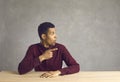 Surprised young black man sitting at desk looking and pointing away at copy space background Royalty Free Stock Photo