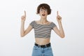 Wow look there. Portrait of curious and impressed intrigued woman in round glasses and cropped top, raising index