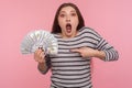 Wow, so much money! Portrait of shocked young woman in striped sweatshirt screaming in amazement and pointing dollar bills