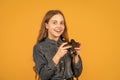 Wow. Surprised teen photographer yellow background. Teen girl holding camera