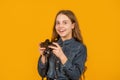 Wow. Surprised teen photographer yellow background. Teen girl holding camera
