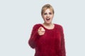 Wow, is that was you? Portrait of surprised beautiful young blond woman in red blouse standing, looking and pointing at camera Royalty Free Stock Photo