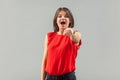 Wow, you are unbelievable! Portrait of surprised beautiful brunette young woman in red shirt standing, pointing and looking at Royalty Free Stock Photo