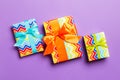 Wrapped Christmas or other holiday handmade present in paper with blue, green and orange ribbon on purple background. Present box Royalty Free Stock Photo