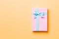 Wrapped Christmas or other holiday handmade present in paper with blue ribbon on orange background. Present box, decoration of Royalty Free Stock Photo