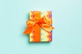 Wrapped Christmas or other holiday handmade present in paper with orange ribbon on blue background. Present box, decoration of Royalty Free Stock Photo
