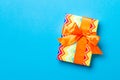 Wrapped Christmas or other holiday handmade present in paper with orange ribbon on blue background. Present box, decoration of Royalty Free Stock Photo
