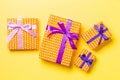 Wrapped Christmas or other holiday handmade present in paper with purple and pink ribbon on yellow background. Present box, Royalty Free Stock Photo