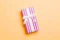 Wrapped Christmas or other holiday handmade present in paper with white ribbon on orange background. Present box, decoration of Royalty Free Stock Photo